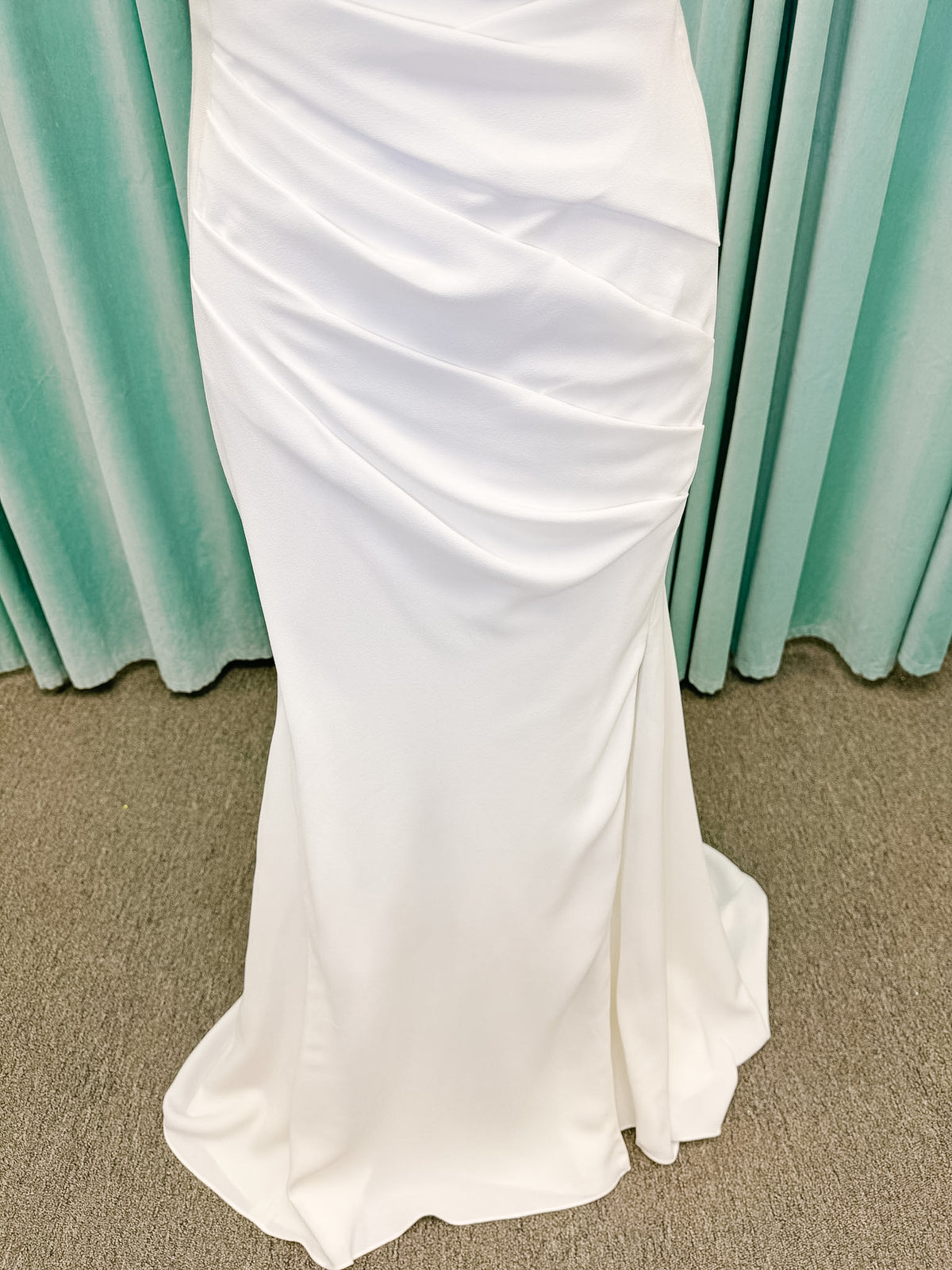 Stella York SY8224 sheath wedding dress on mannequin with spaghetti straps, draped scoop neckline, ruched crepe bodice, front slit, and detachable back cowl