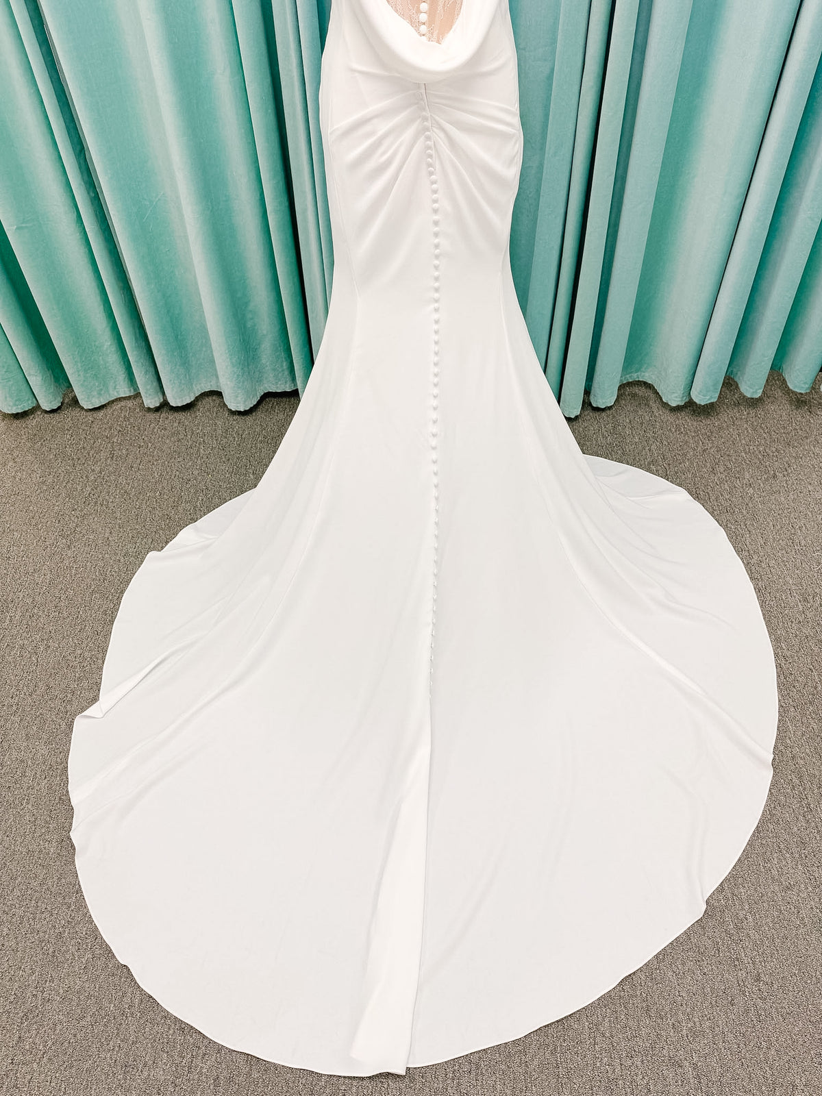 Stella York SY8224 sheath wedding dress on mannequin with spaghetti straps, draped scoop neckline, ruched crepe bodice, front slit, and detachable back cowl