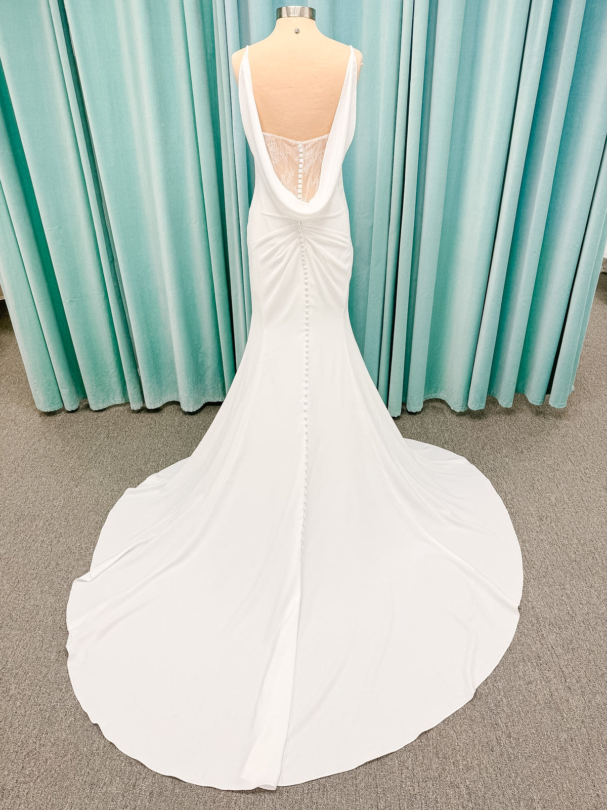 Stella York SY8224 sheath wedding dress on mannequin with spaghetti straps, draped scoop neckline, ruched crepe bodice, front slit, and detachable back cowl