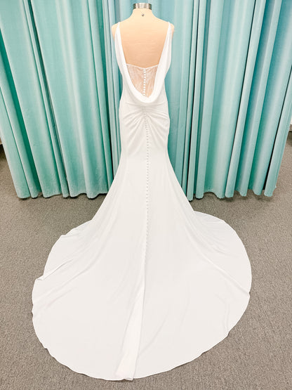Stella York SY8224 sheath wedding dress on mannequin with spaghetti straps, draped scoop neckline, ruched crepe bodice, front slit, and detachable back cowl