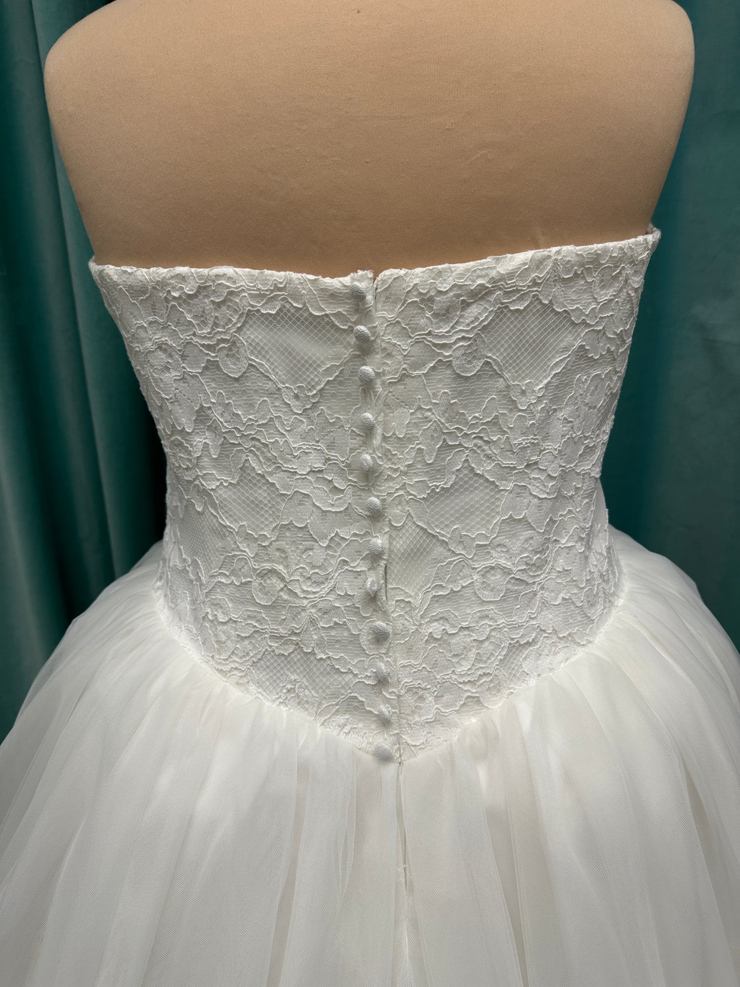 Plus size strapless lace ballgown wedding dress with cat-eye neckline, basque waist, full tulle skirt, and detachable satin bow by Stella York Style SY8189