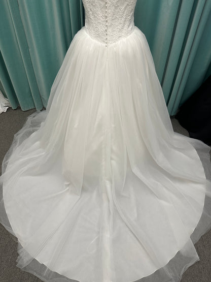 Plus size strapless lace ballgown wedding dress with cat-eye neckline, basque waist, full tulle skirt, and detachable satin bow by Stella York Style SY8189