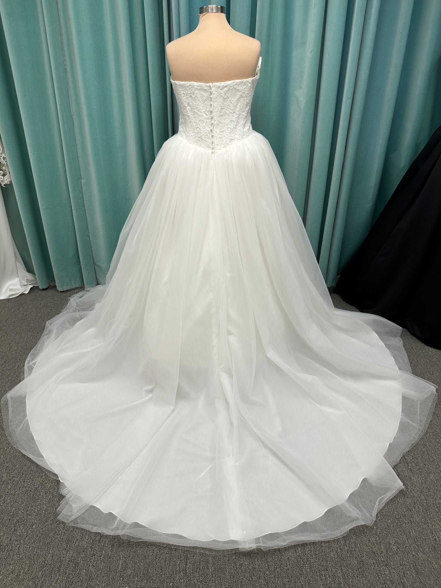 Plus size strapless lace ballgown wedding dress with cat-eye neckline, basque waist, full tulle skirt, and detachable satin bow by Stella York Style SY8189