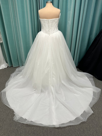 Plus size strapless lace ballgown wedding dress with cat-eye neckline, basque waist, full tulle skirt, and detachable satin bow by Stella York Style SY8189