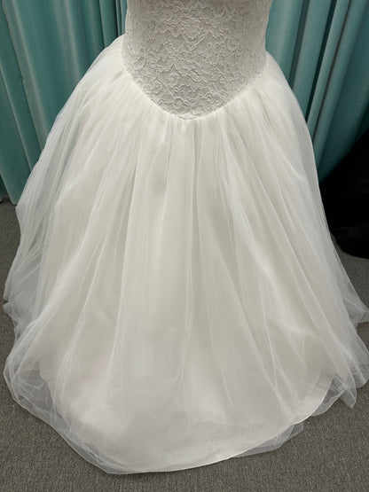 Plus size strapless lace ballgown wedding dress with cat-eye neckline, basque waist, full tulle skirt, and detachable satin bow by Stella York Style SY8189