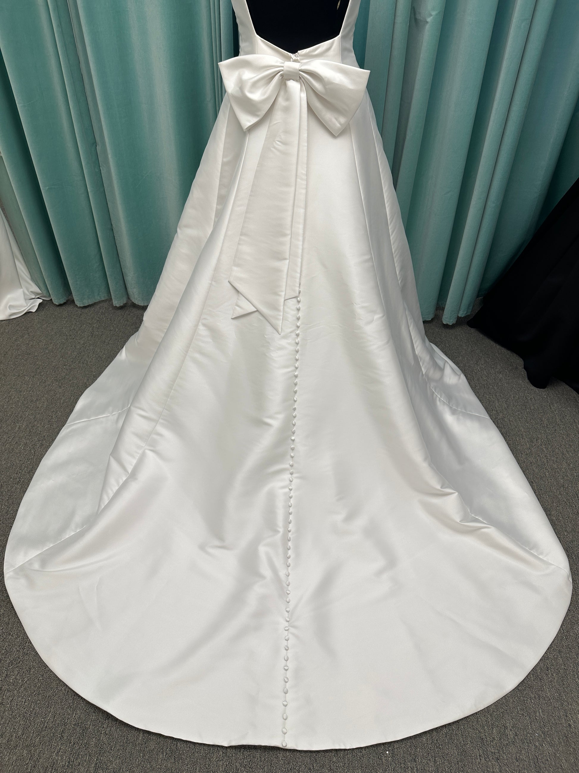 Minimalist Mikado A-line wedding dress with square neckline, clean seams, subtle side cutouts, and detachable oversized bow at the back