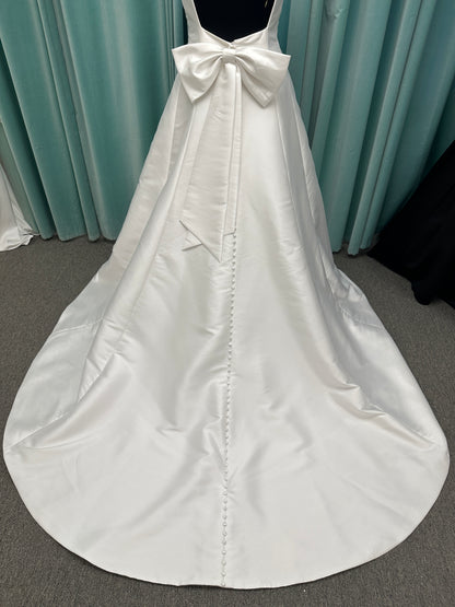 Minimalist Mikado A-line wedding dress with square neckline, clean seams, subtle side cutouts, and detachable oversized bow at the back