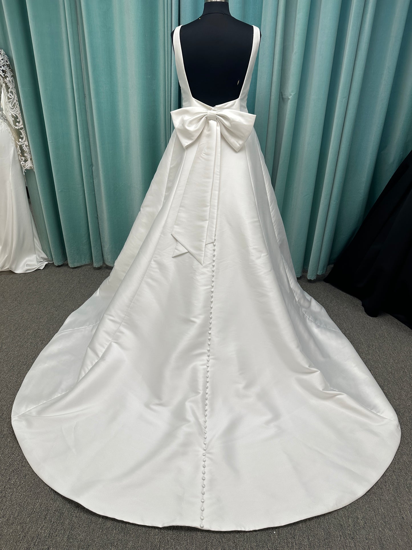 Minimalist Mikado A-line wedding dress with square neckline, clean seams, subtle side cutouts, and detachable oversized bow at the back
