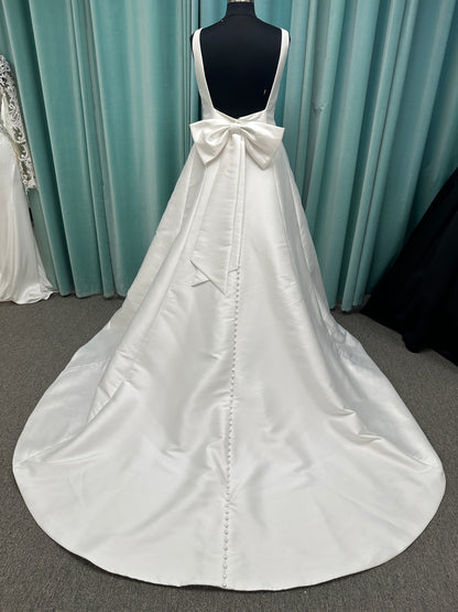 Minimalist Mikado A-line wedding dress with square neckline, clean seams, subtle side cutouts, and detachable oversized bow at the back