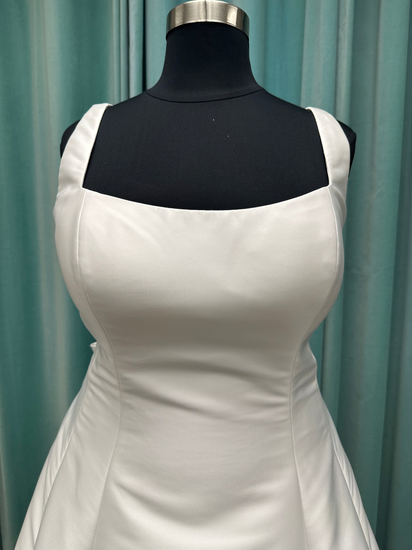 Minimalist Mikado A-line wedding dress with square neckline, clean seams, subtle side cutouts, and detachable oversized bow at the back