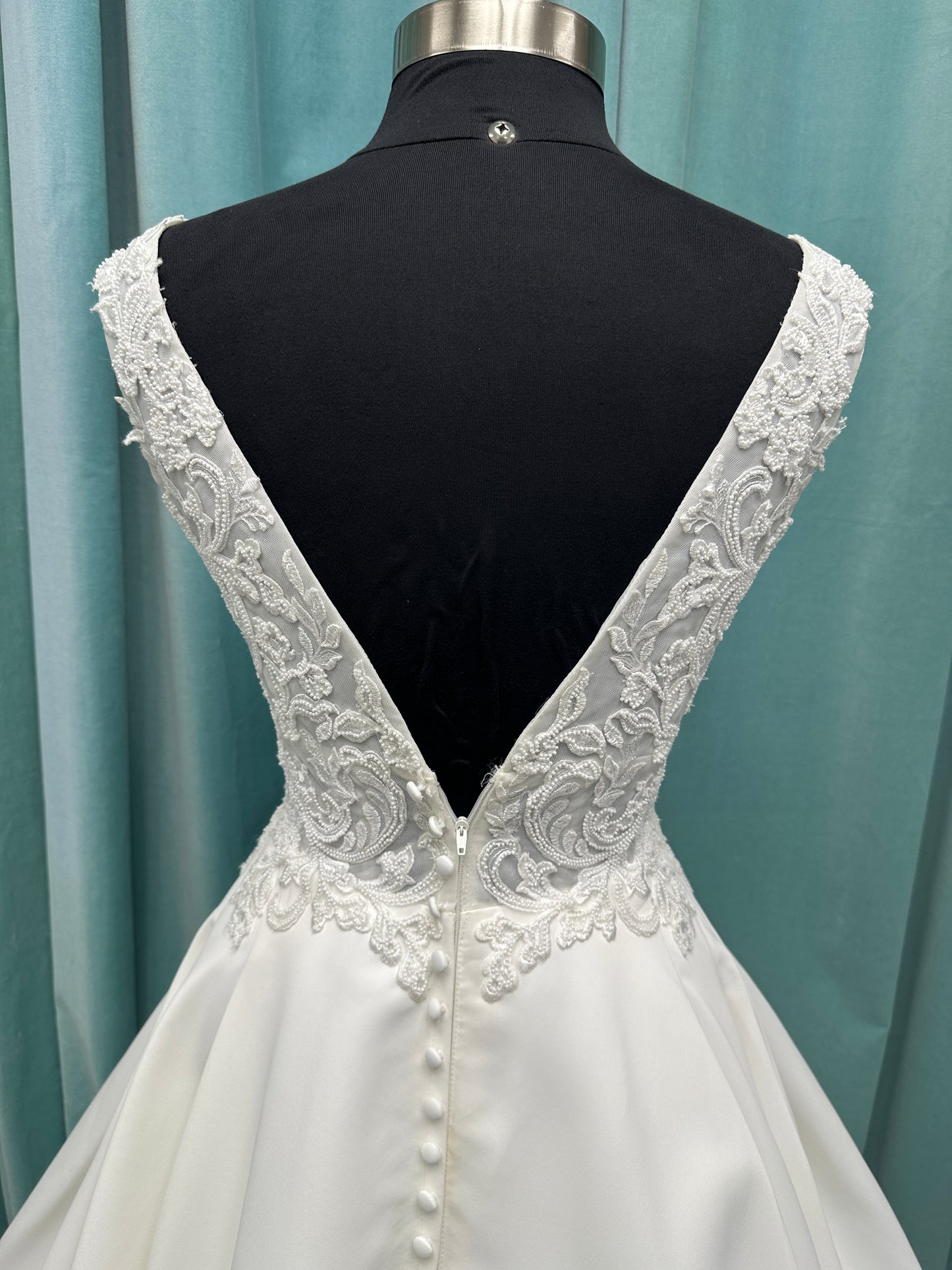 Satin A-line wedding dress with deep V-neckline, lace bodice, illusion tulle inset, and flowing skirt with pockets and long train