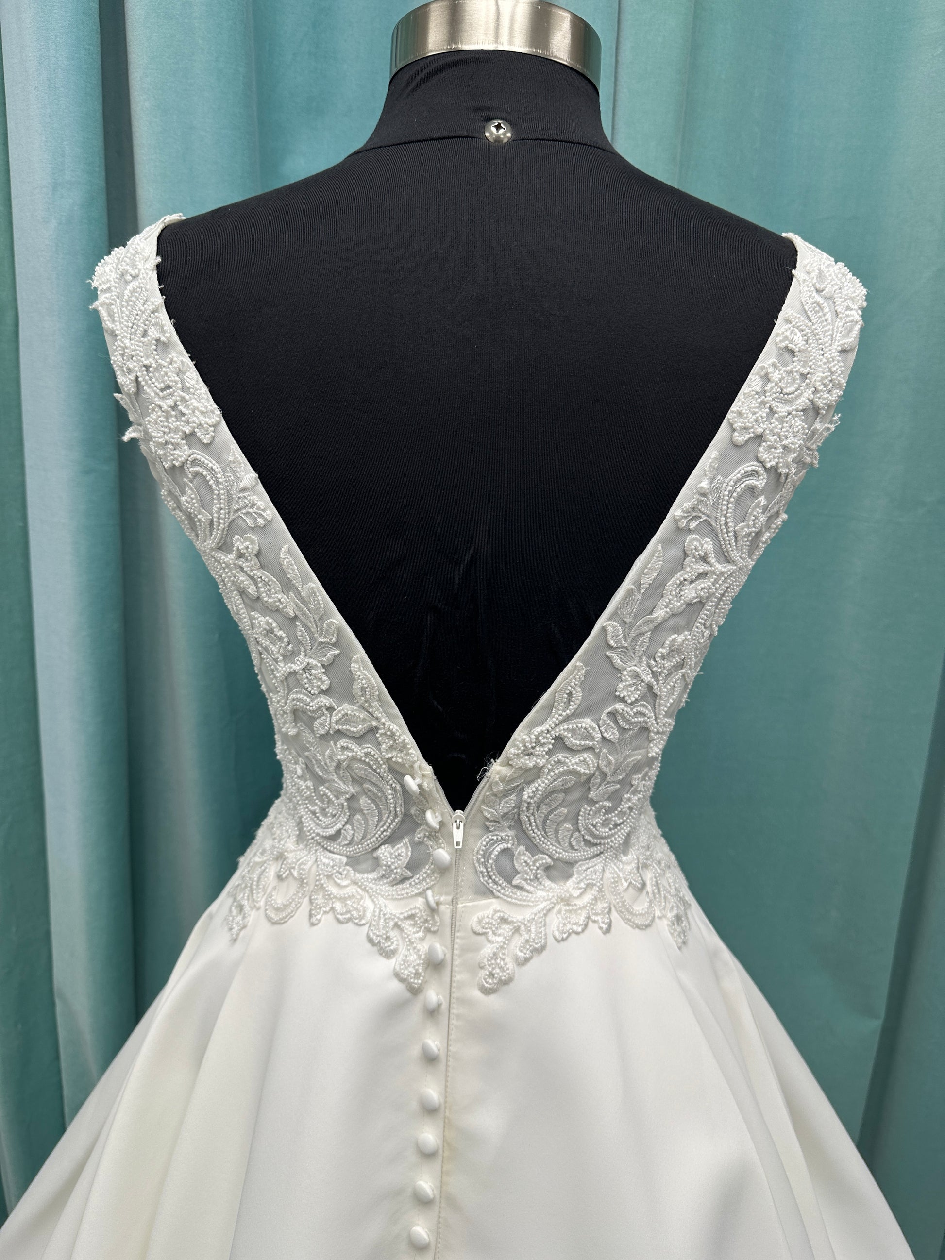 Satin A-line wedding dress with deep V-neckline, lace bodice, illusion tulle inset, and flowing skirt with pockets and long train