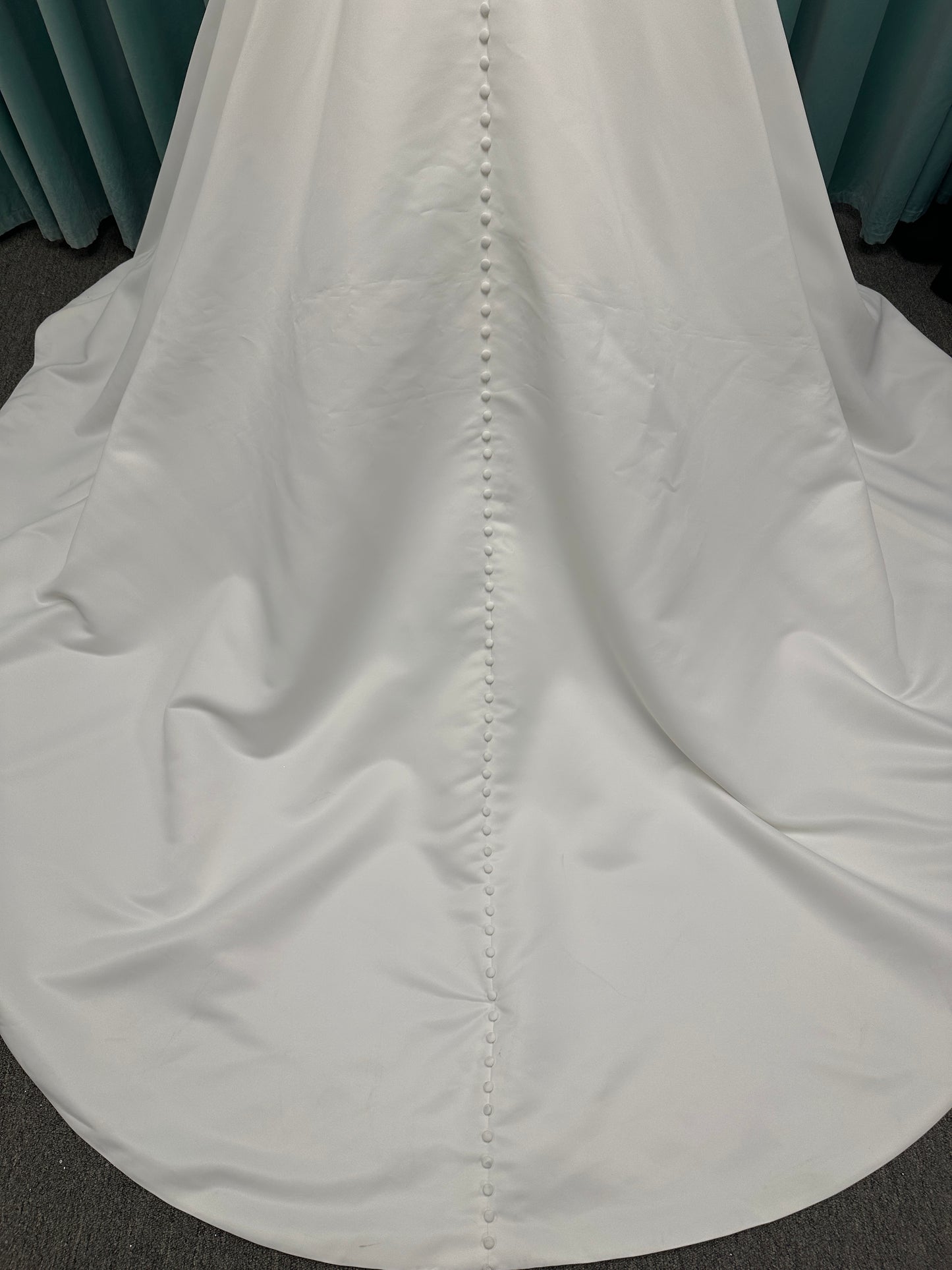 Satin A-line wedding dress with deep V-neckline, lace bodice, illusion tulle inset, and flowing skirt with pockets and long train