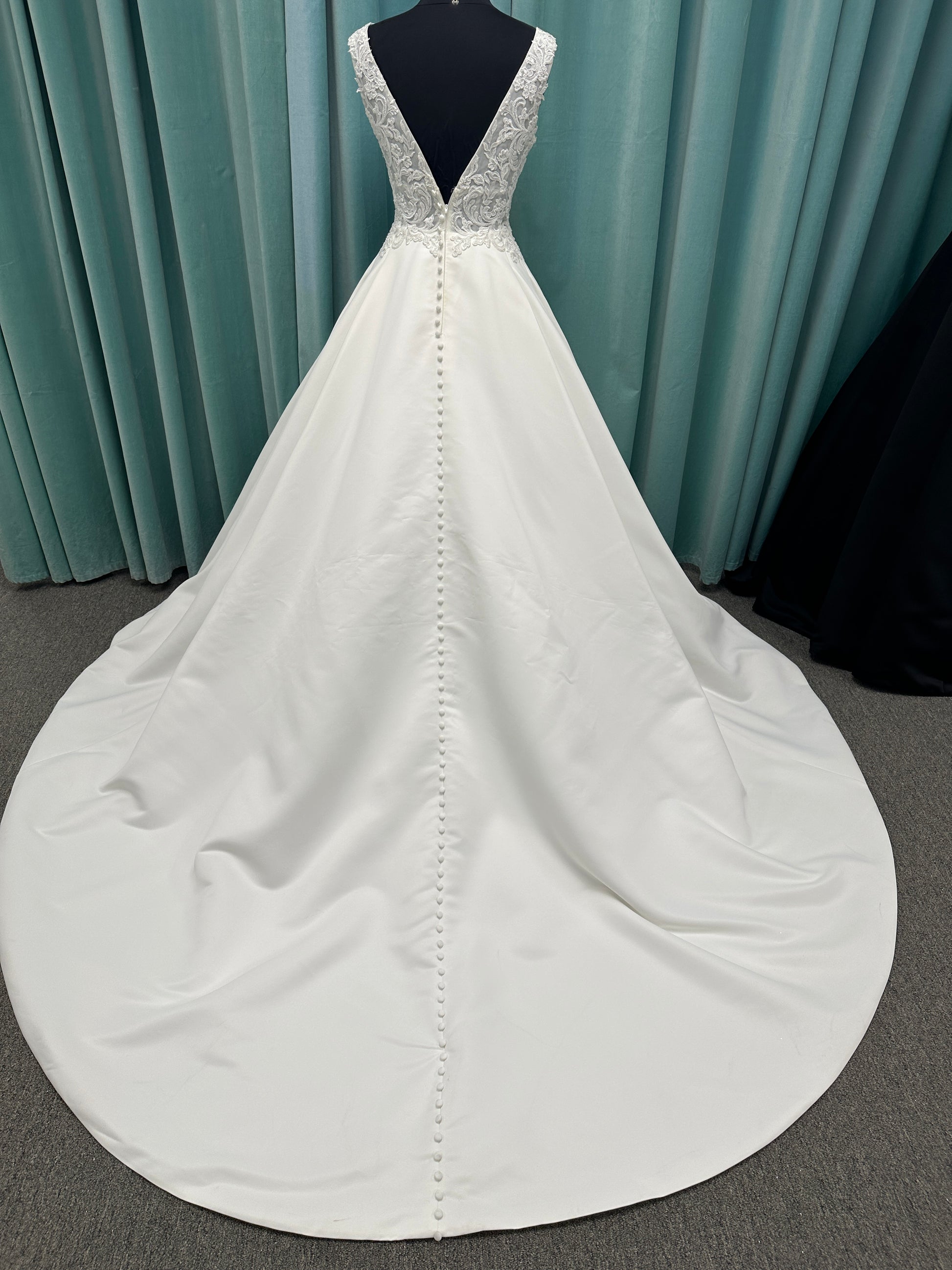 Satin A-line wedding dress with deep V-neckline, lace bodice, illusion tulle inset, and flowing skirt with pockets and long train
