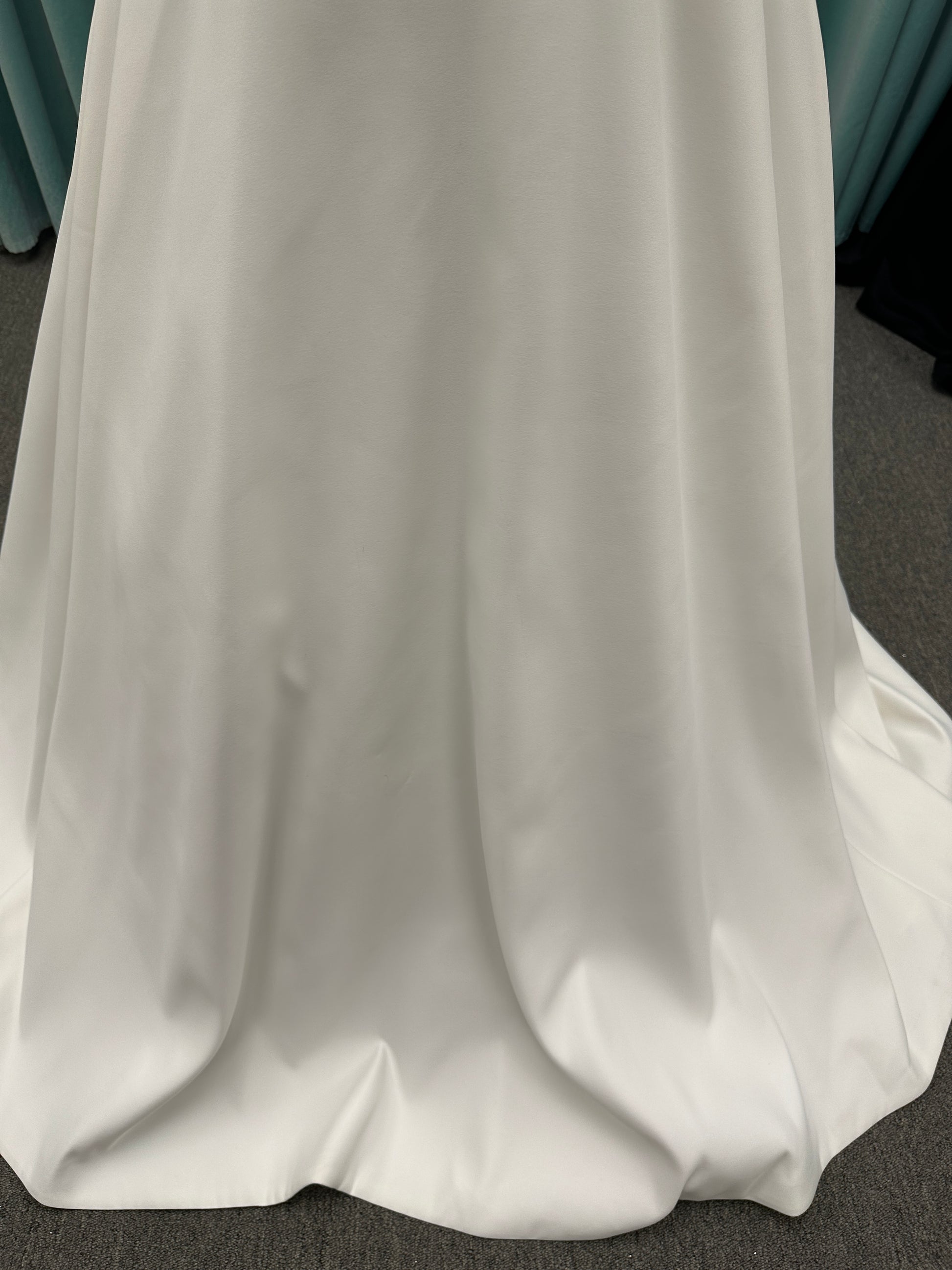 Satin A-line wedding dress with deep V-neckline, lace bodice, illusion tulle inset, and flowing skirt with pockets and long train