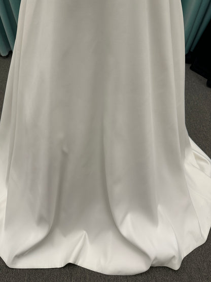 Satin A-line wedding dress with deep V-neckline, lace bodice, illusion tulle inset, and flowing skirt with pockets and long train