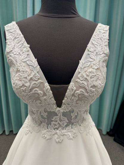 Satin A-line wedding dress with deep V-neckline, lace bodice, illusion tulle inset, and flowing skirt with pockets and long train