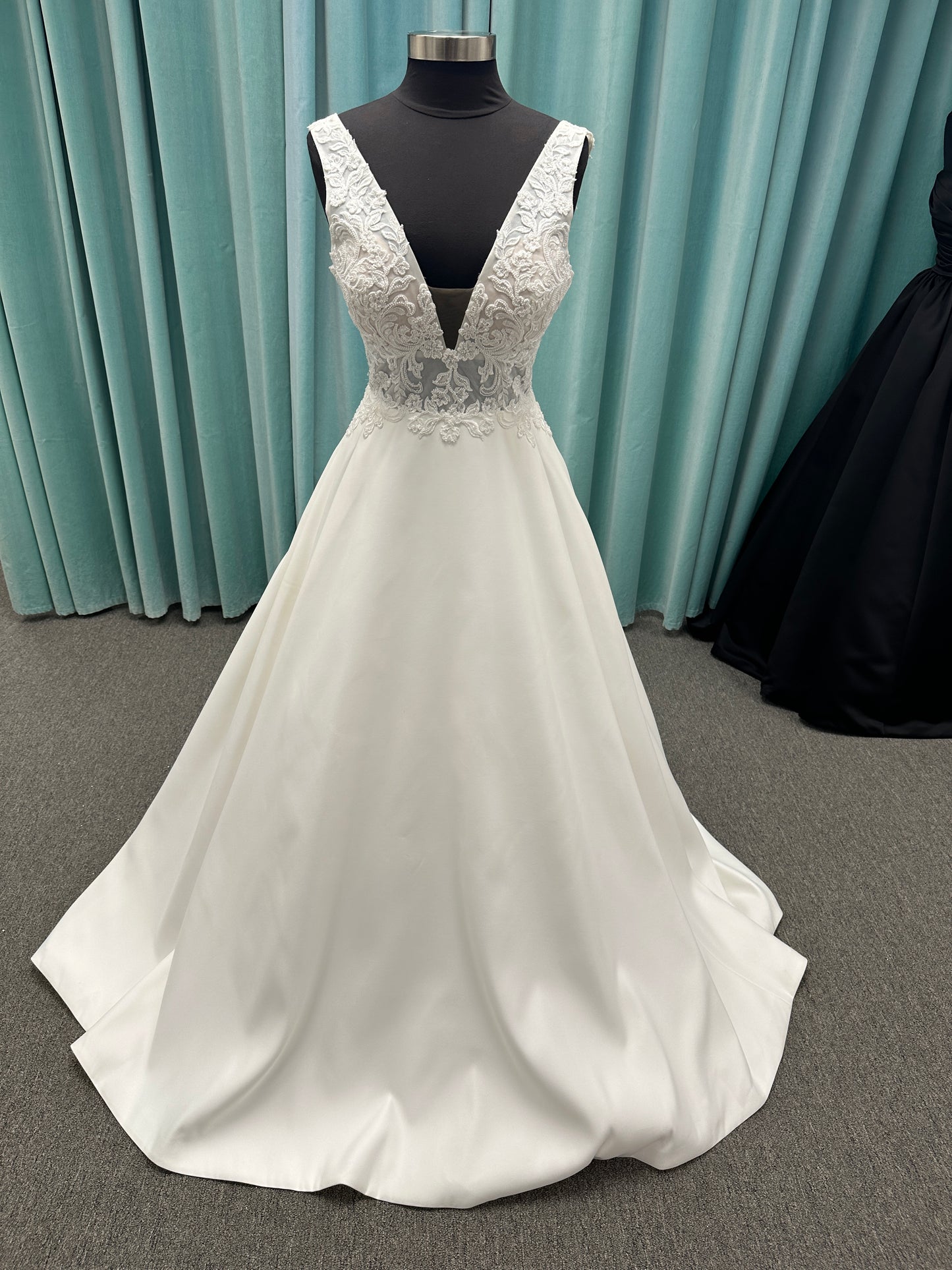 Satin A-line wedding dress with deep V-neckline, lace bodice, illusion tulle inset, and flowing skirt with pockets and long train