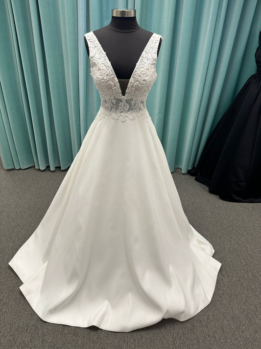 Satin A-line wedding dress with deep V-neckline, lace bodice, illusion tulle inset, and flowing skirt with pockets and long train