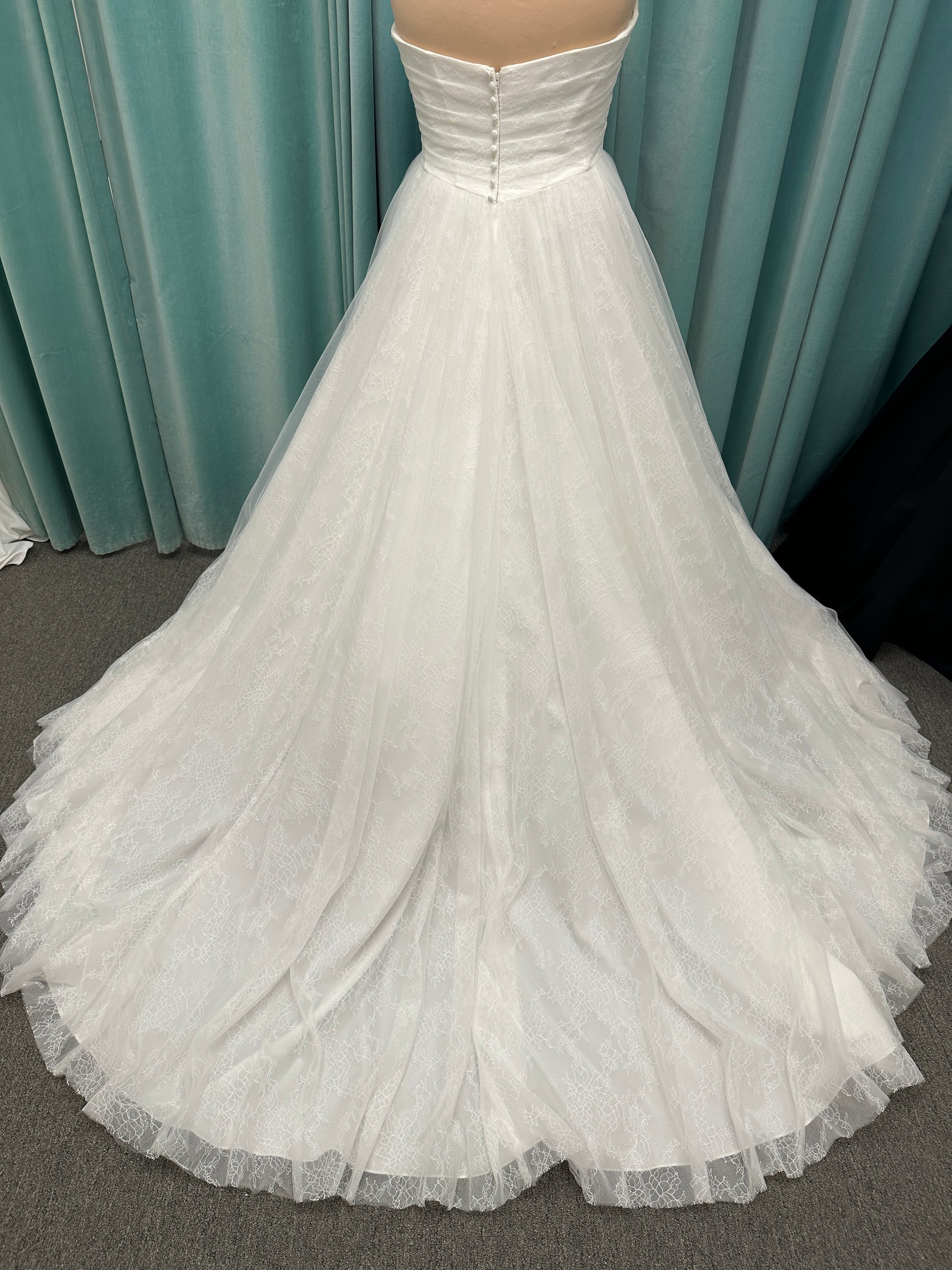Plus size strapless A-line wedding dress with ruched tulle bodice, Chantilly lace detailing, basque waist, and flowing tulle skirt with train