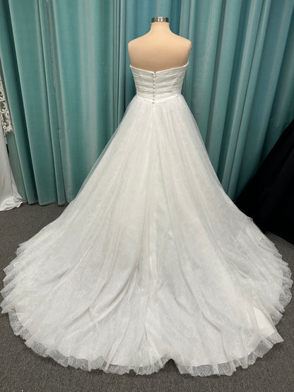 Plus size strapless A-line wedding dress with ruched tulle bodice, Chantilly lace detailing, basque waist, and flowing tulle skirt with train