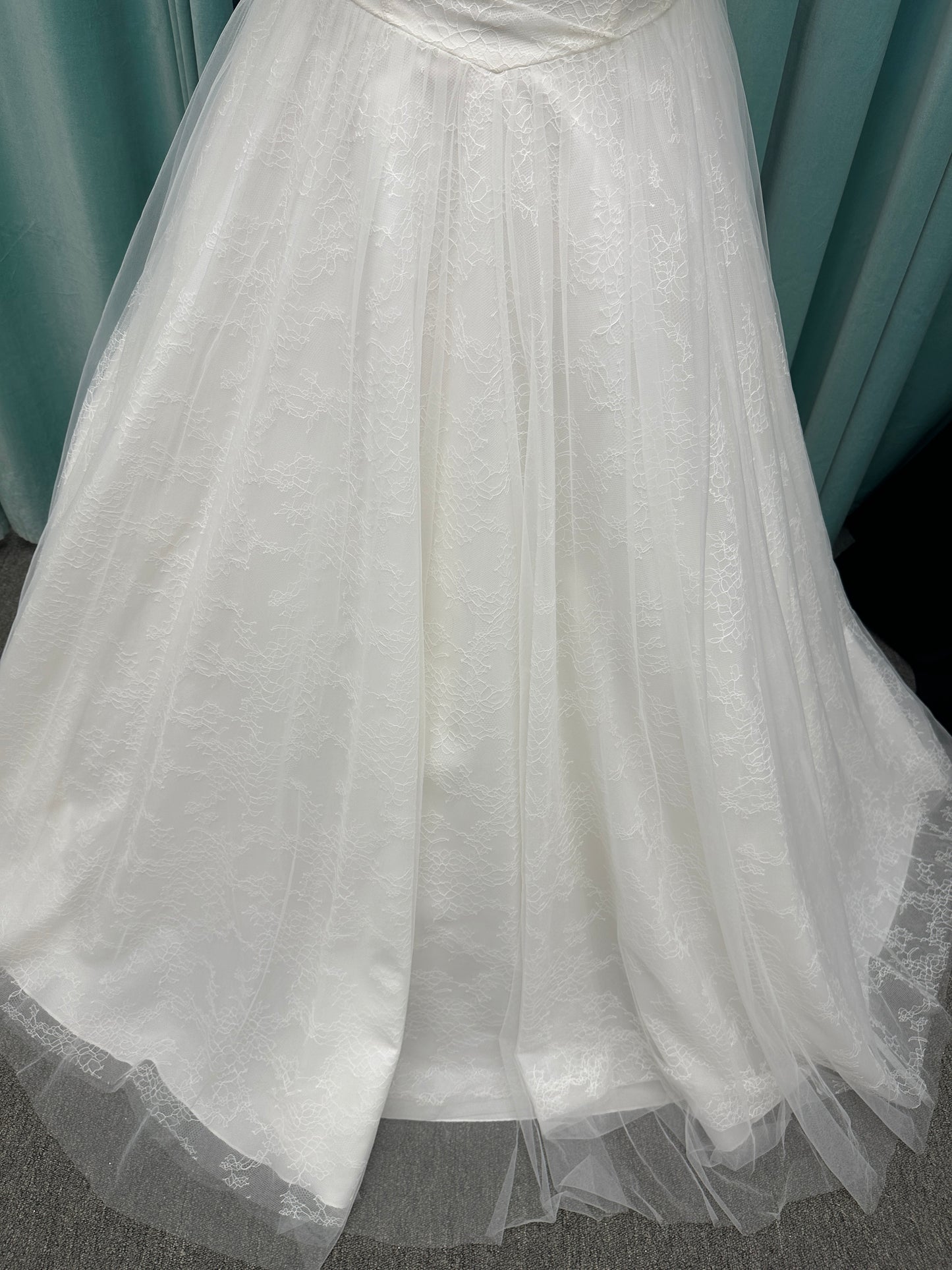 Plus size strapless A-line wedding dress with ruched tulle bodice, Chantilly lace detailing, basque waist, and flowing tulle skirt with train