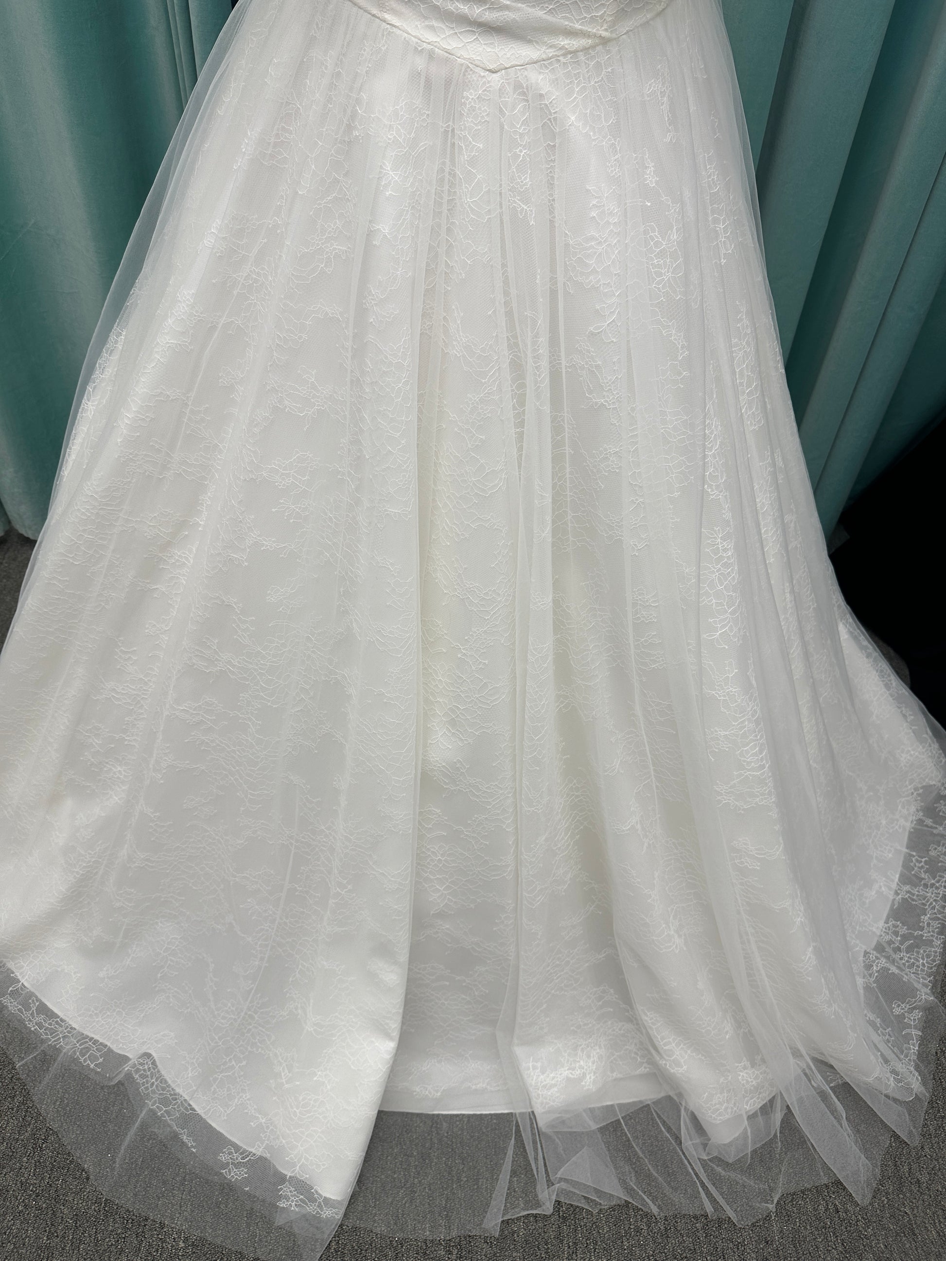Plus size strapless A-line wedding dress with ruched tulle bodice, Chantilly lace detailing, basque waist, and flowing tulle skirt with train
