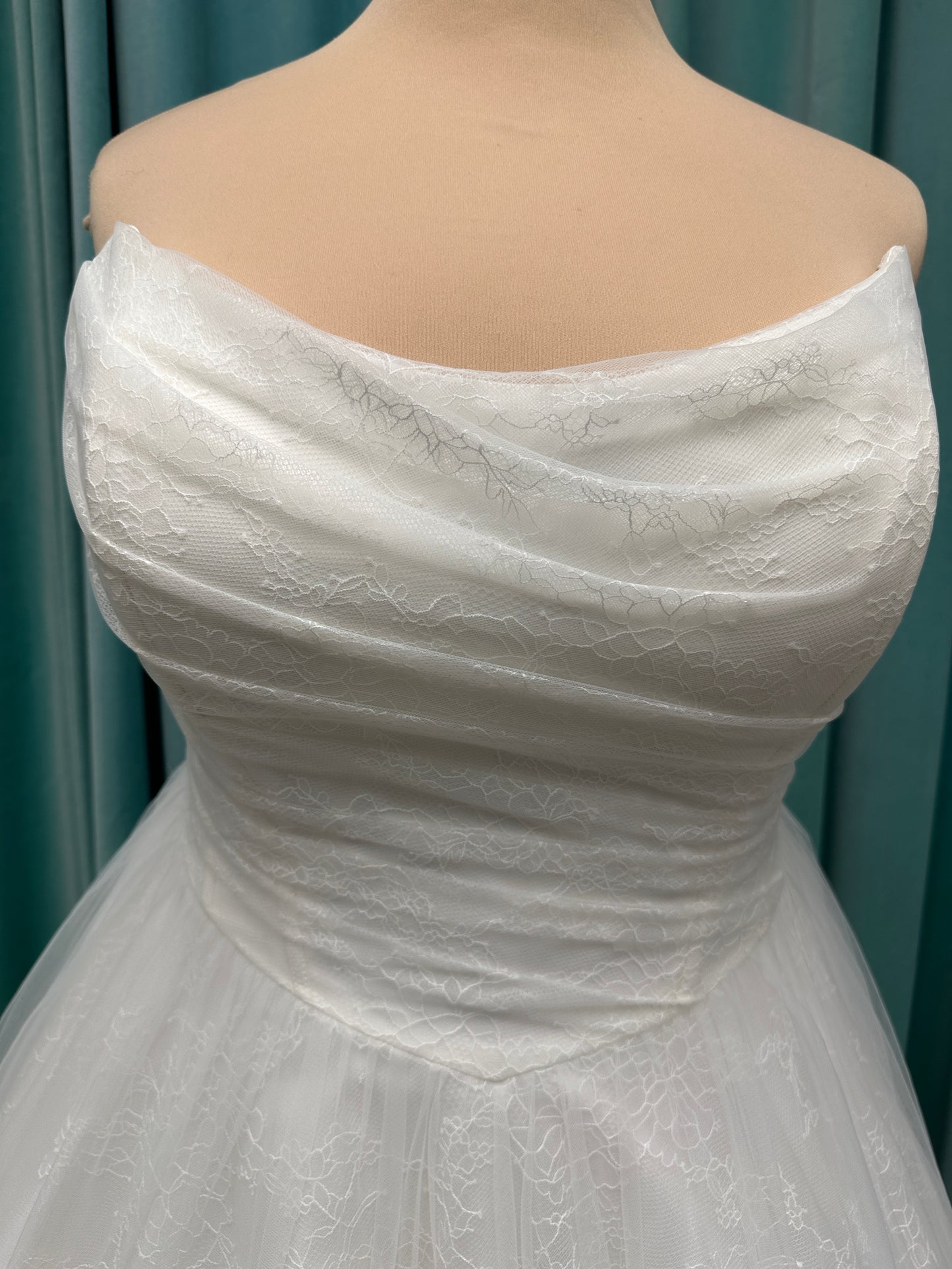 Plus size strapless A-line wedding dress with ruched tulle bodice, Chantilly lace detailing, basque waist, and flowing tulle skirt with train