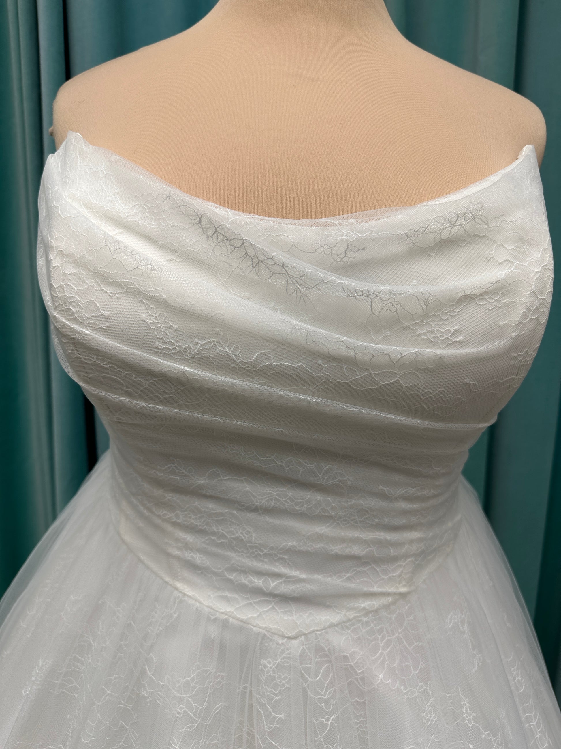 Plus size strapless A-line wedding dress with ruched tulle bodice, Chantilly lace detailing, basque waist, and flowing tulle skirt with train