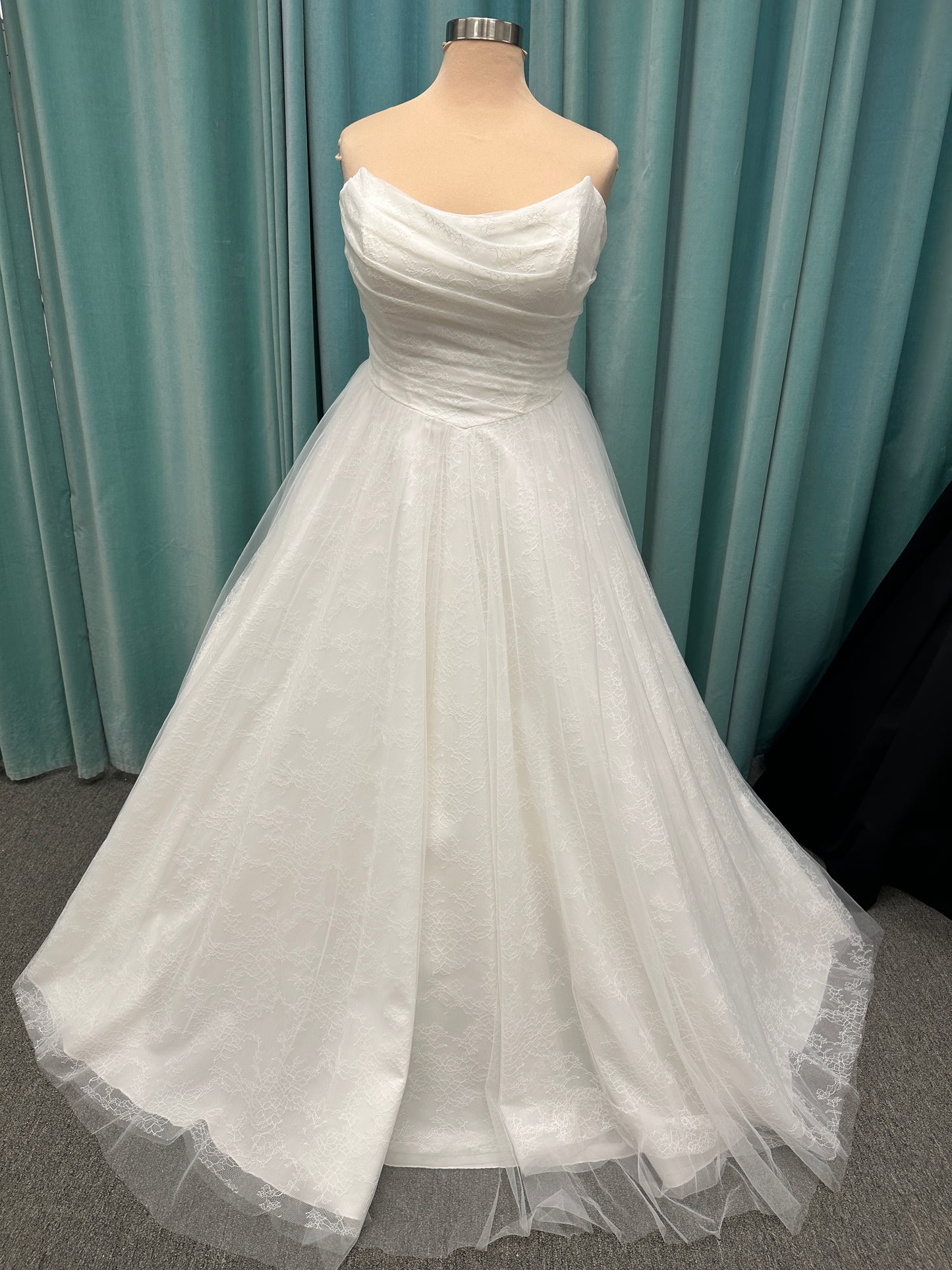Plus size strapless A-line wedding dress with ruched tulle bodice, Chantilly lace detailing, basque waist, and flowing tulle skirt with train