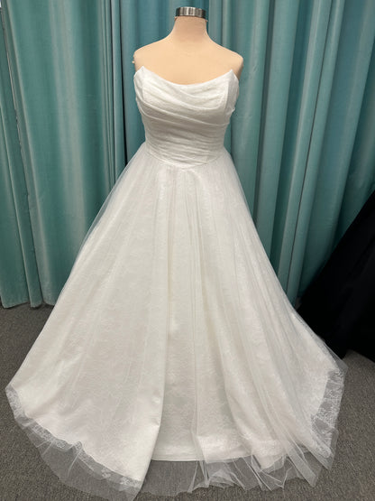 Plus size strapless A-line wedding dress with ruched tulle bodice, Chantilly lace detailing, basque waist, and flowing tulle skirt with train