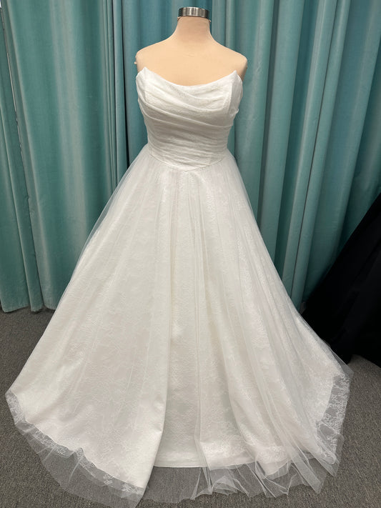 Plus size strapless A-line wedding dress with ruched tulle bodice, Chantilly lace detailing, basque waist, and flowing tulle skirt with train
