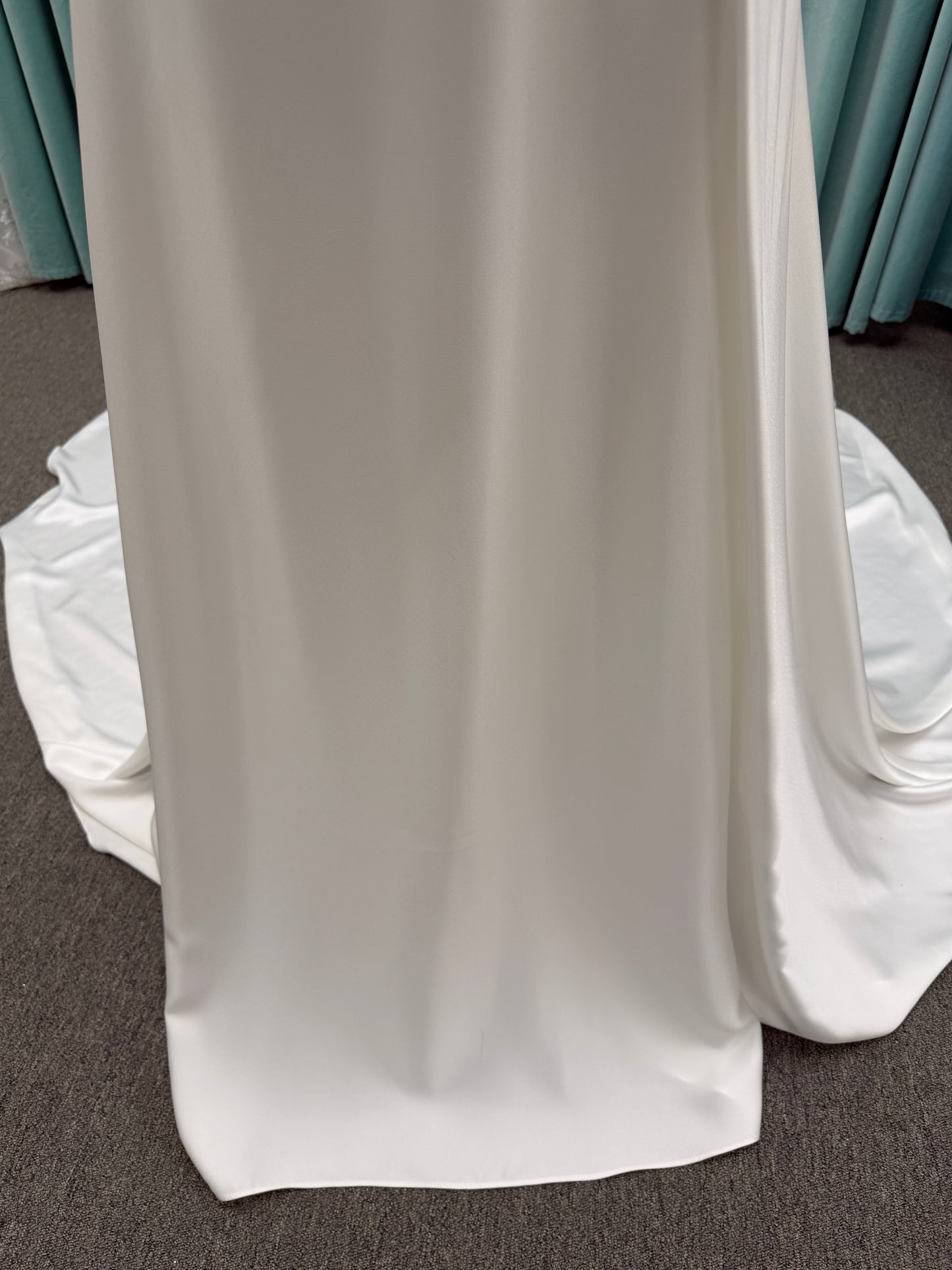 Stella York SY8110 ivory satin A-line wedding dress on mannequin with square neckline, shoulder straps, ruched bodice, and scoop back with fabric-covered buttons.
