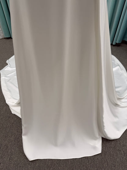 Stella York SY8110 ivory satin A-line wedding dress on mannequin with square neckline, shoulder straps, ruched bodice, and scoop back with fabric-covered buttons.
