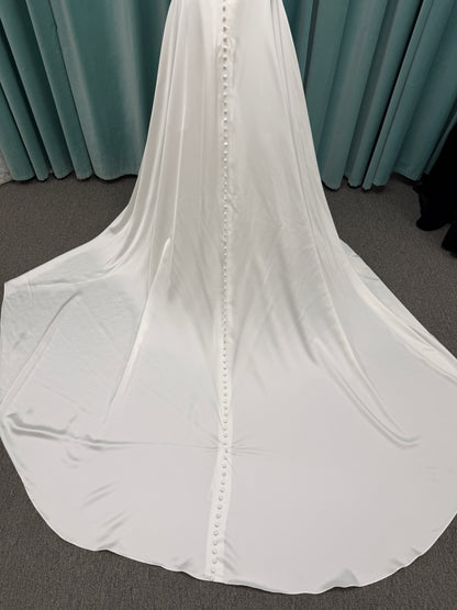 Stella York SY8110 ivory satin A-line wedding dress on mannequin with square neckline, shoulder straps, ruched bodice, and scoop back with fabric-covered buttons.
