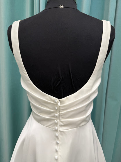 Stella York SY8110 ivory satin A-line wedding dress on mannequin with square neckline, shoulder straps, ruched bodice, and scoop back with fabric-covered buttons.
