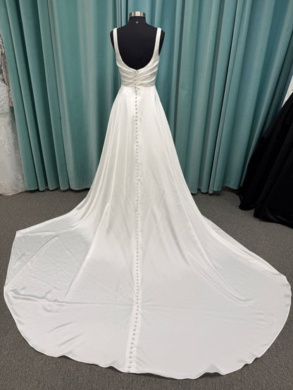 Stella York SY8110 ivory satin A-line wedding dress on mannequin with square neckline, shoulder straps, ruched bodice, and scoop back with fabric-covered buttons.
