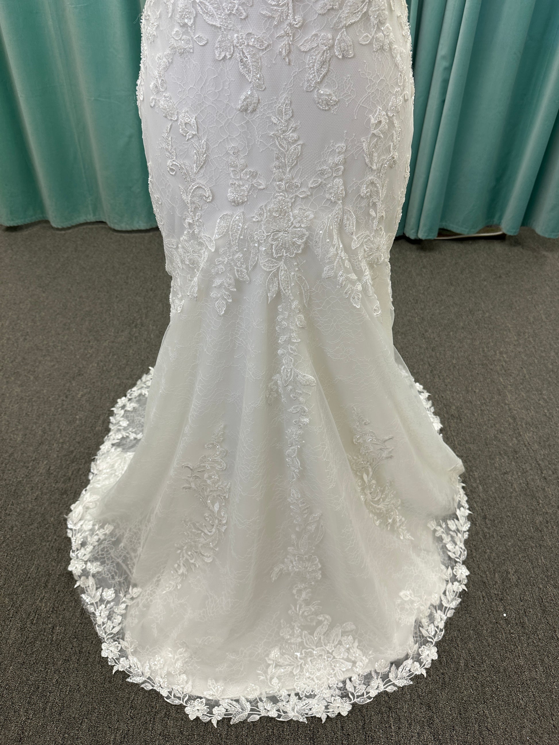 Starr ivory lace fit-and-flare wedding dress on mannequin with sweetheart neckline, delicate straps, and low open back with sweeping train.
