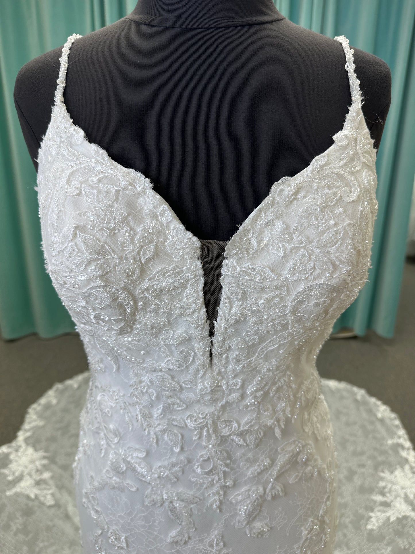 Starr ivory lace fit-and-flare wedding dress on mannequin with sweetheart neckline, delicate straps, and low open back with sweeping train.
