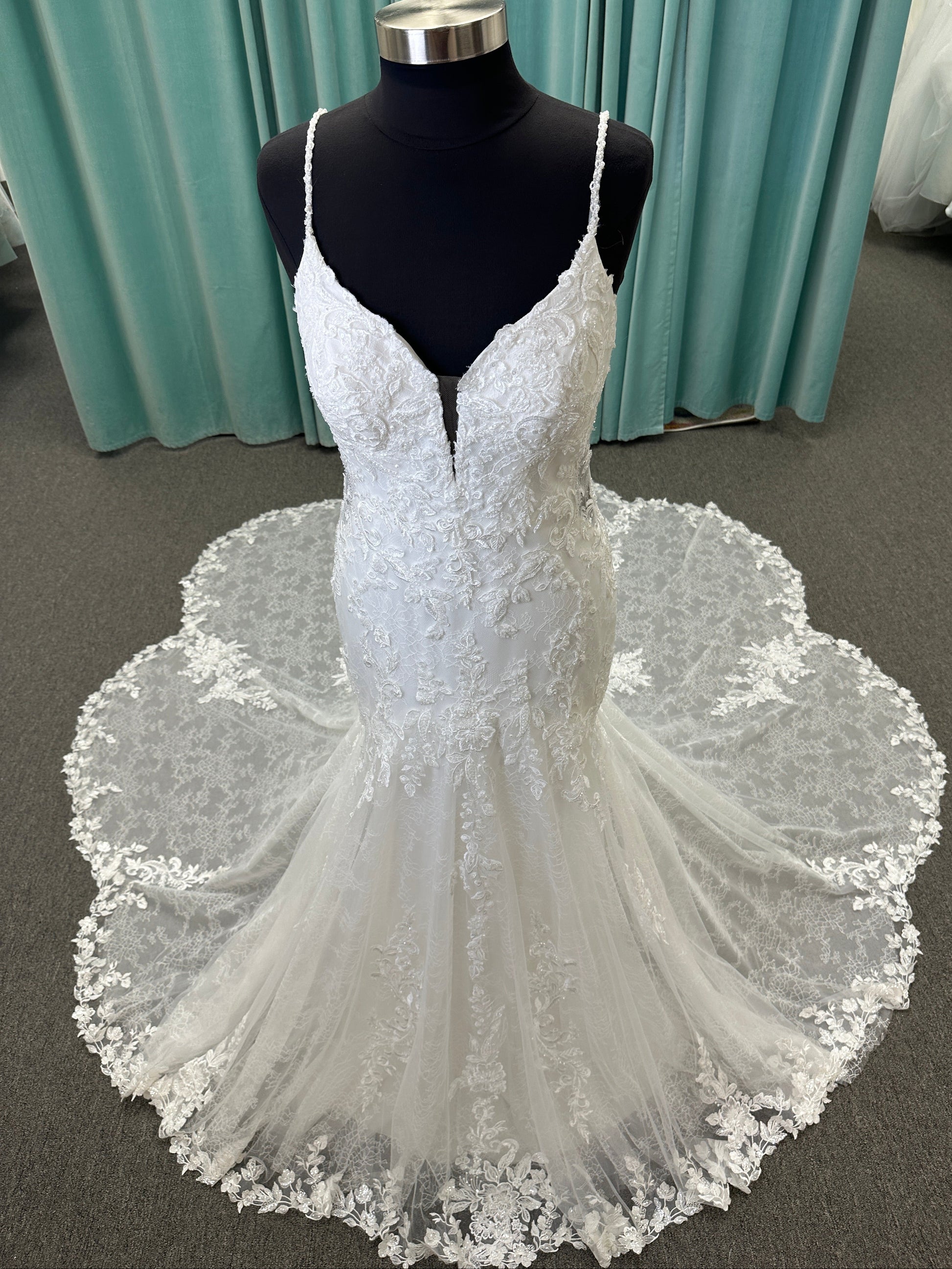 Starr ivory lace fit-and-flare wedding dress on mannequin with sweetheart neckline, delicate straps, and low open back with sweeping train.
