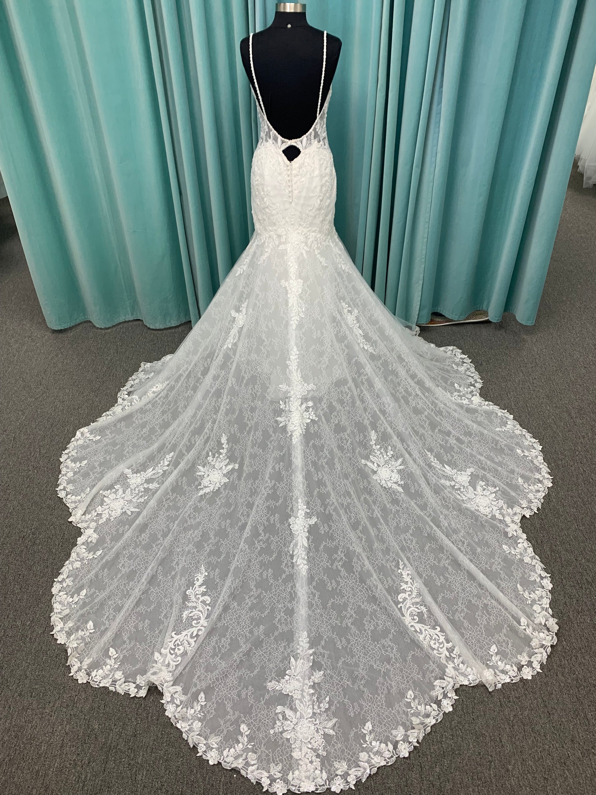 Starr ivory lace fit-and-flare wedding dress on mannequin with sweetheart neckline, delicate straps, and low open back with sweeping train.
