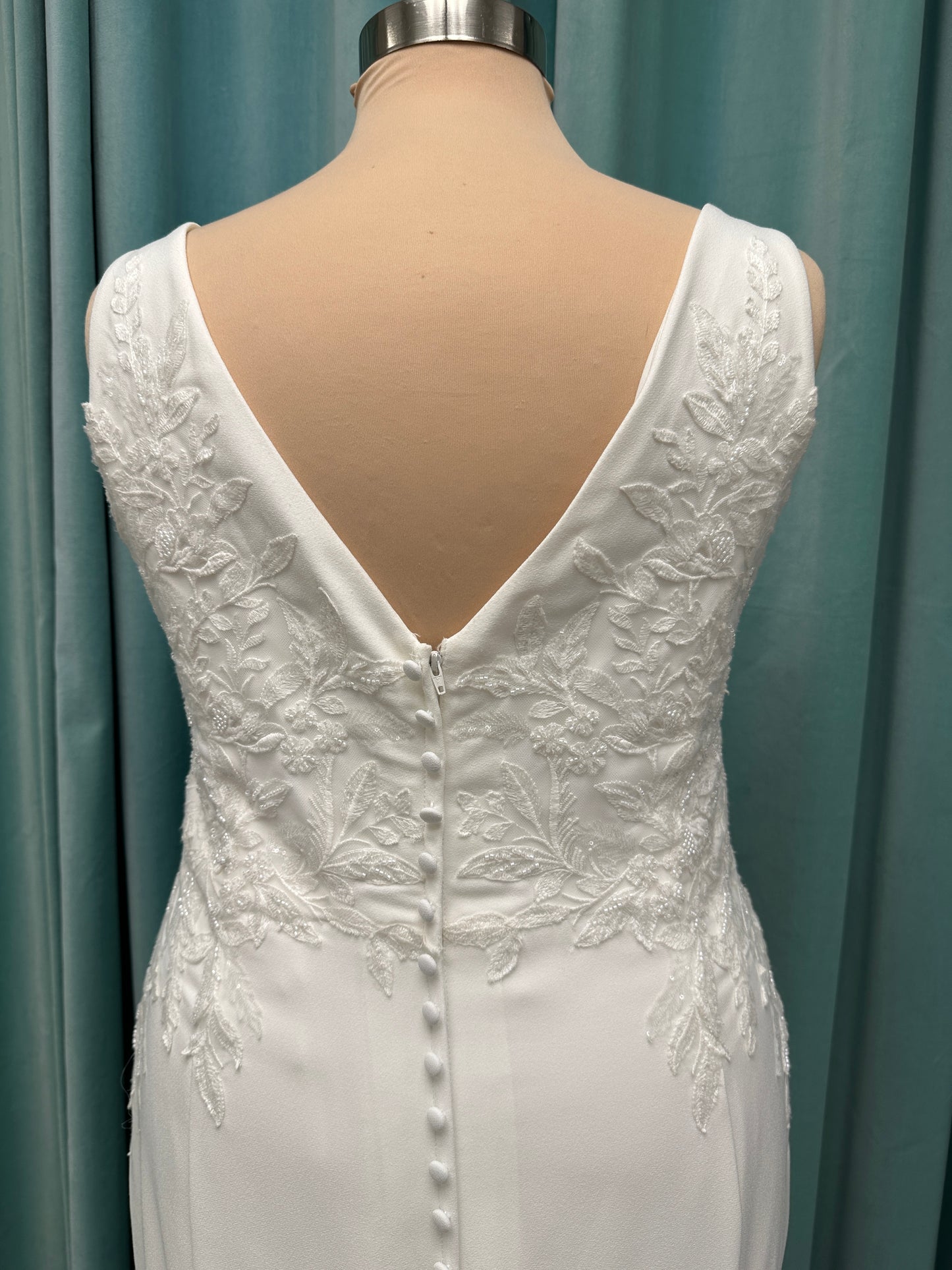 Stella York 7774 column sheath wedding dress with plunging neckline, lace appliqués, side cutouts, and crepe skirt with train