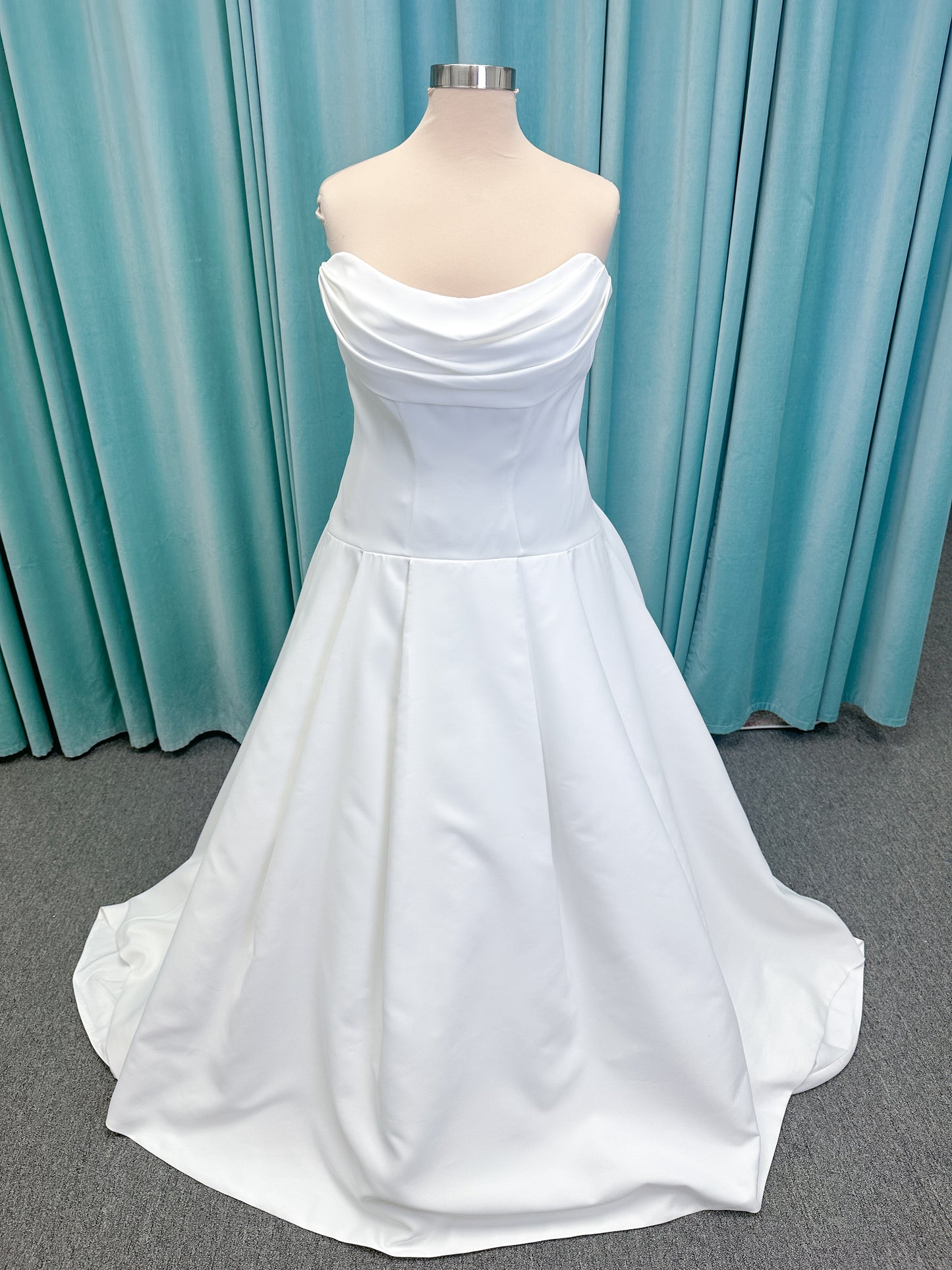 Morilee 15080 Tiana A-line wedding dress in satin with cowl-draped strapless neckline, drop waist, contoured seaming, pleated skirt, and covered buttons to hem.