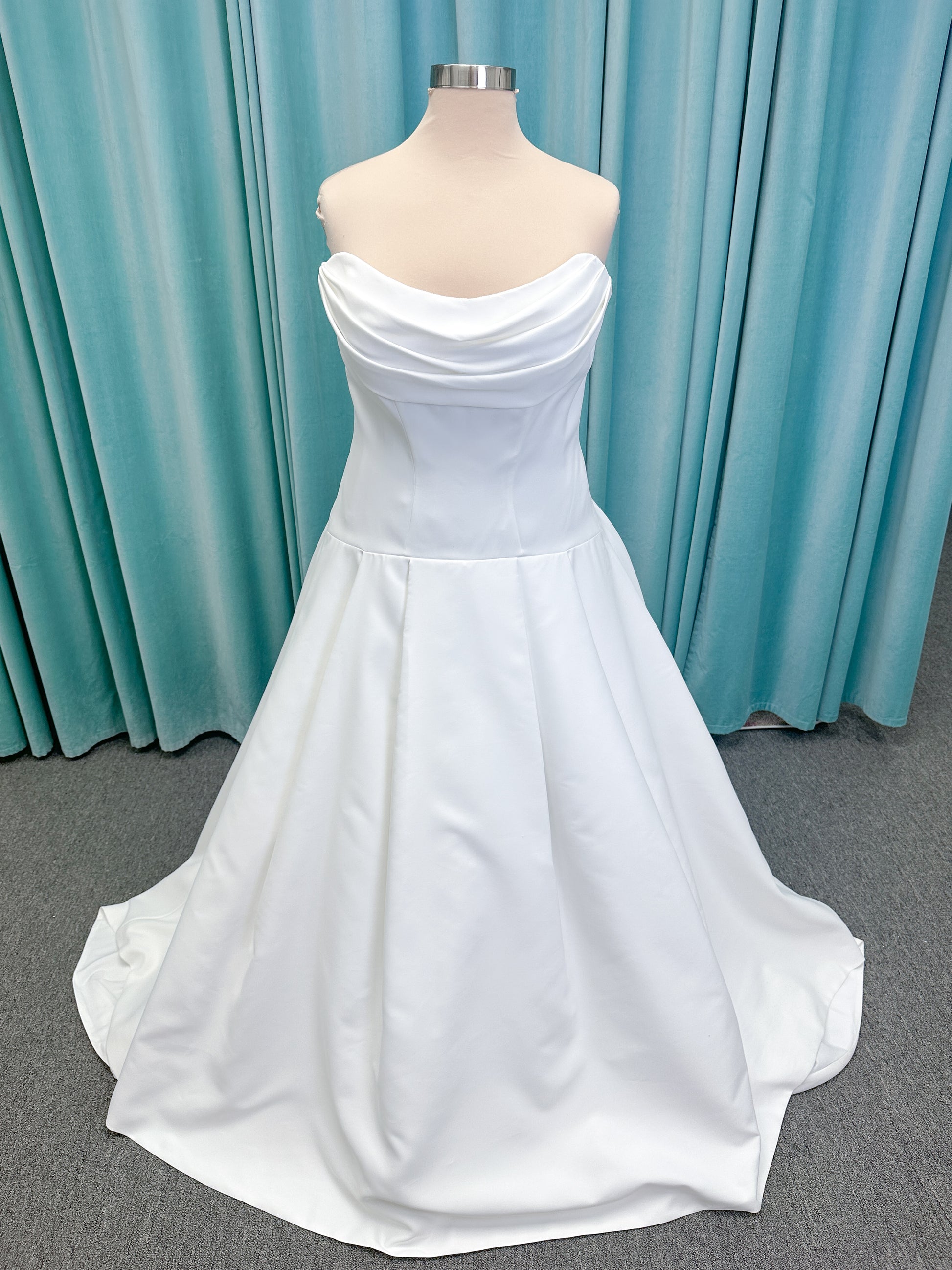 Morilee 15080 Tiana A-line wedding dress in satin with cowl-draped strapless neckline, drop waist, contoured seaming, pleated skirt, and covered buttons to hem.