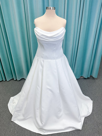 Morilee 15080 Tiana A-line wedding dress in satin with cowl-draped strapless neckline, drop waist, contoured seaming, pleated skirt, and covered buttons to hem.