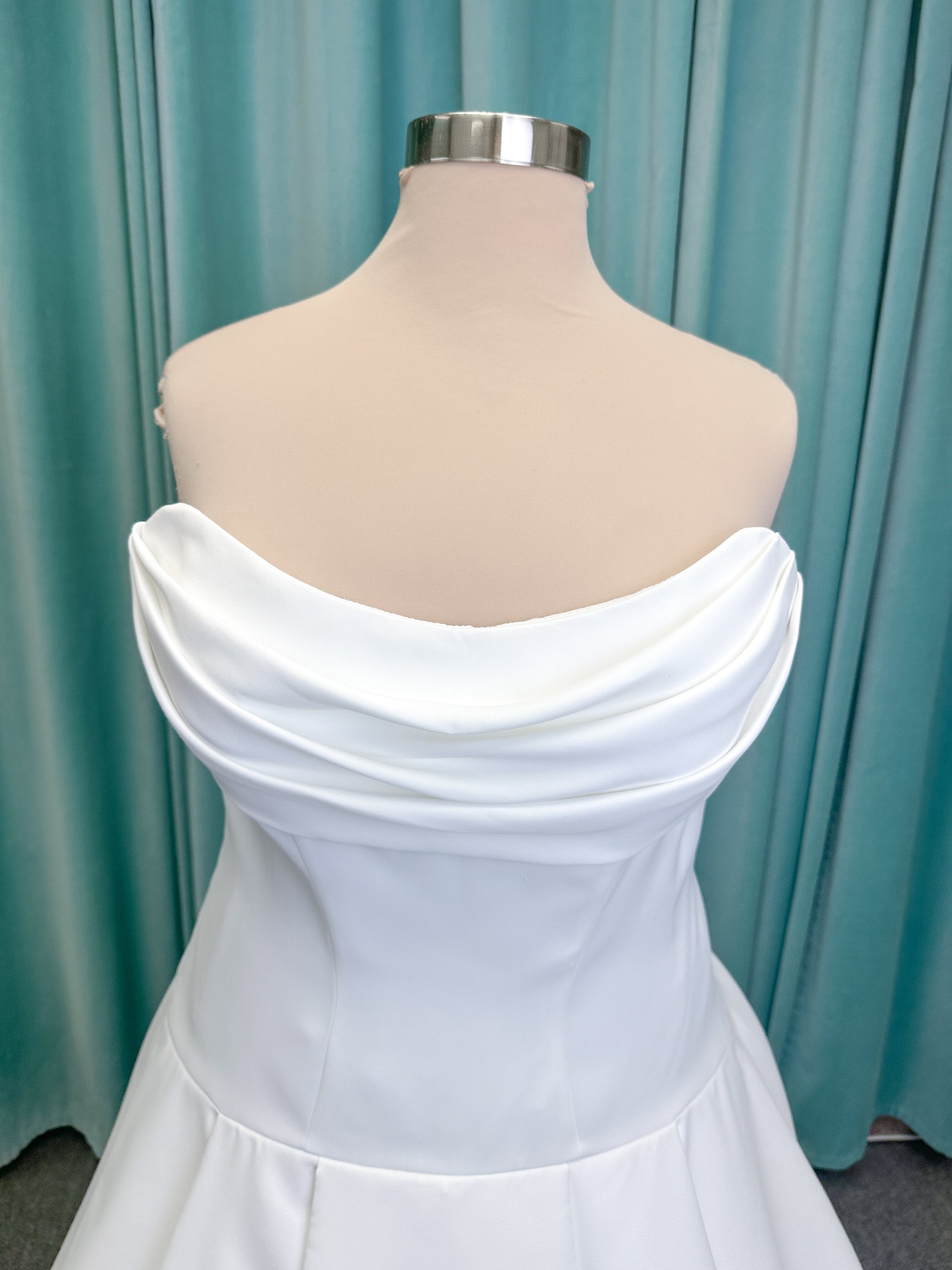 Morilee 15080 Tiana A-line wedding dress in satin with cowl-draped strapless neckline, drop waist, contoured seaming, pleated skirt, and covered buttons to hem.