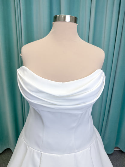 Morilee 15080 Tiana A-line wedding dress in satin with cowl-draped strapless neckline, drop waist, contoured seaming, pleated skirt, and covered buttons to hem.