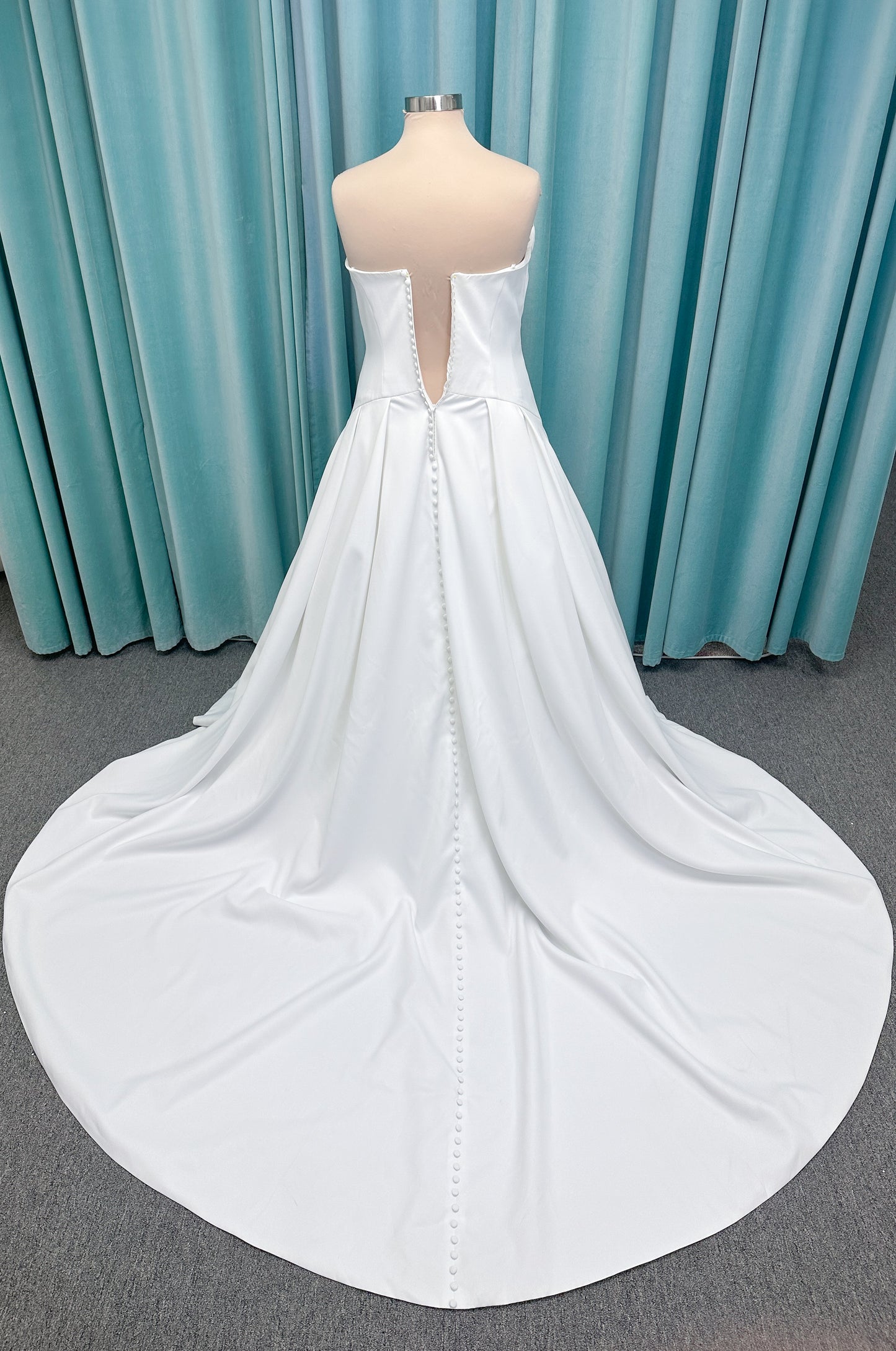 Morilee 15080 Tiana A-line wedding dress in satin with cowl-draped strapless neckline, drop waist, contoured seaming, pleated skirt, and covered buttons to hem.
