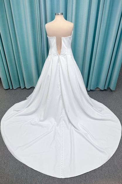 Morilee 15080 Tiana A-line wedding dress in satin with cowl-draped strapless neckline, drop waist, contoured seaming, pleated skirt, and covered buttons to hem.