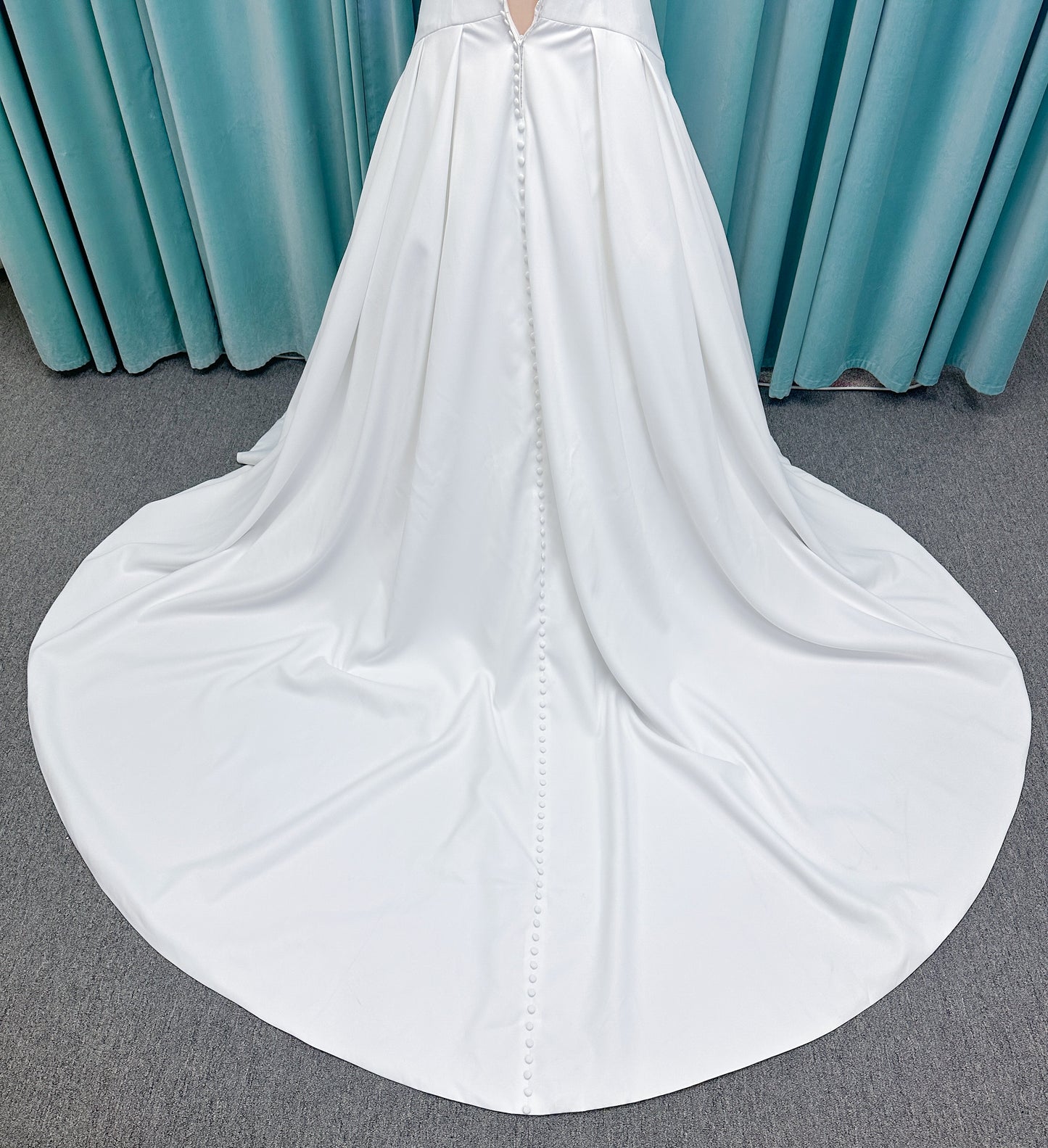 Morilee 15080 Tiana A-line wedding dress in satin with cowl-draped strapless neckline, drop waist, contoured seaming, pleated skirt, and covered buttons to hem.